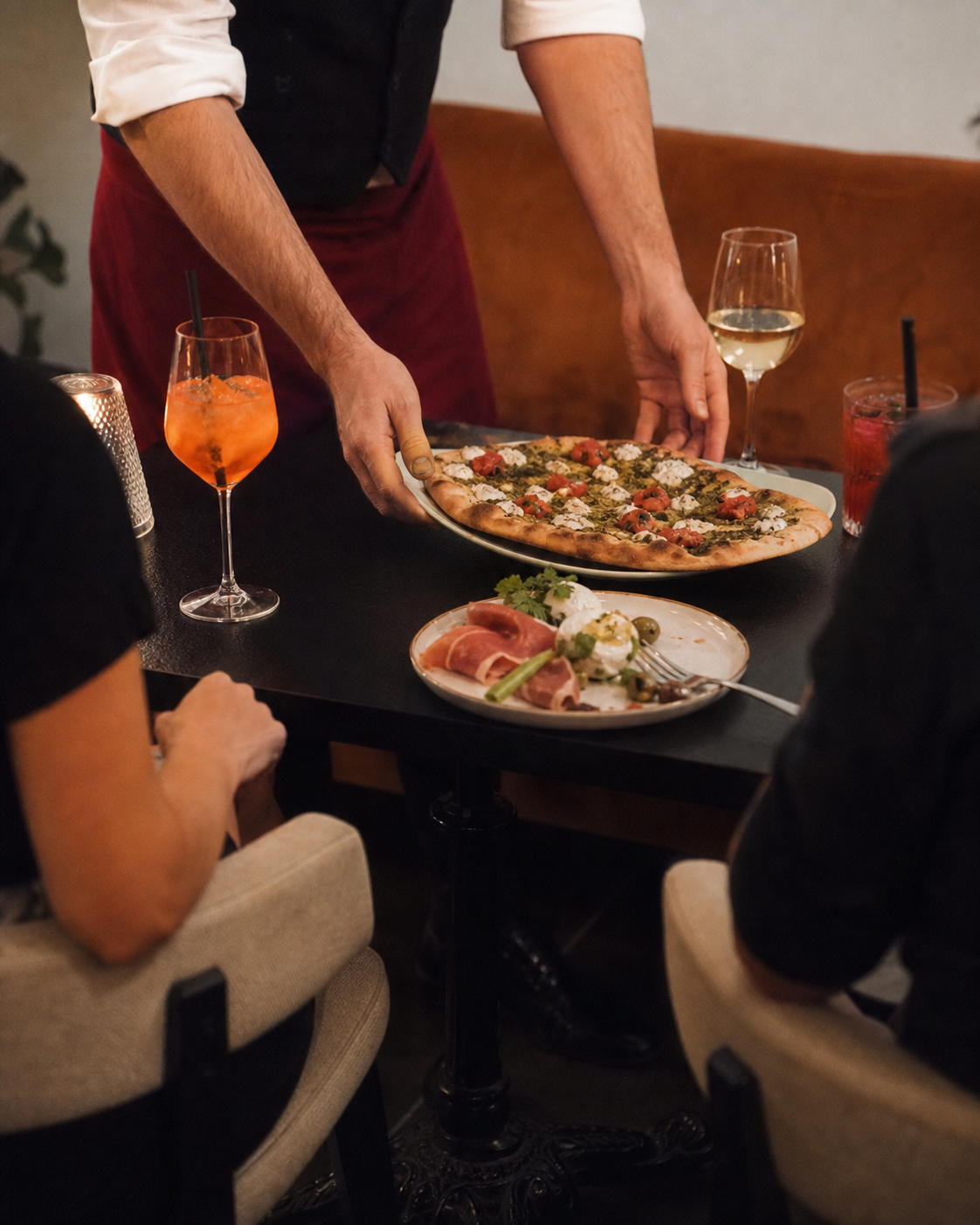 Une pinsa apportée à des convives dans le restaurant
